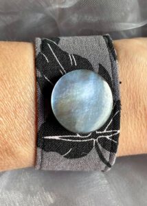 Grau-schwarzes Armband mit Permuttknopf